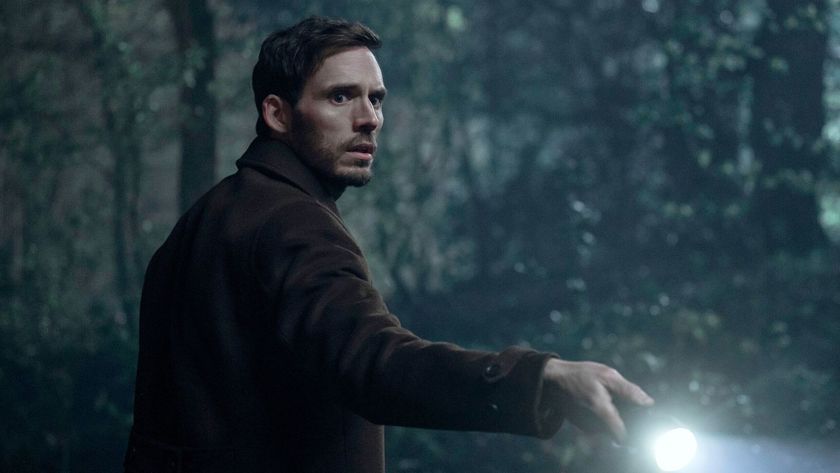 Sam Claflin shines a torch in a snowy forest 