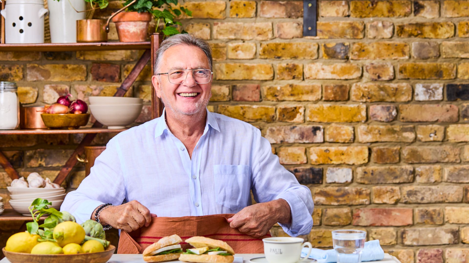 an image of chef Raymond Blanc sitting down to eat a sandwhich and coffee from Paul's bakery