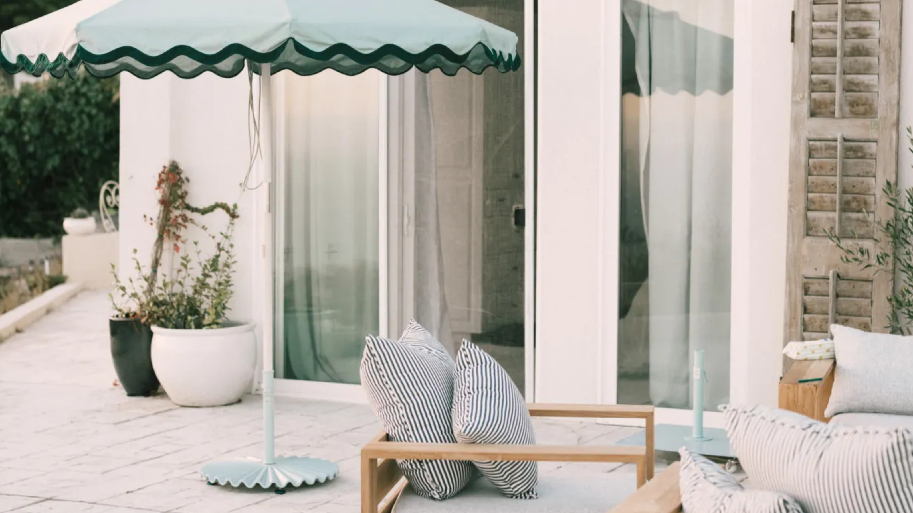 Business &amp; Pleasure Co. Molded Parasol Stand in sage on a patio of a modern white-painted house