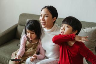 An adult and two children sitting on a couch together