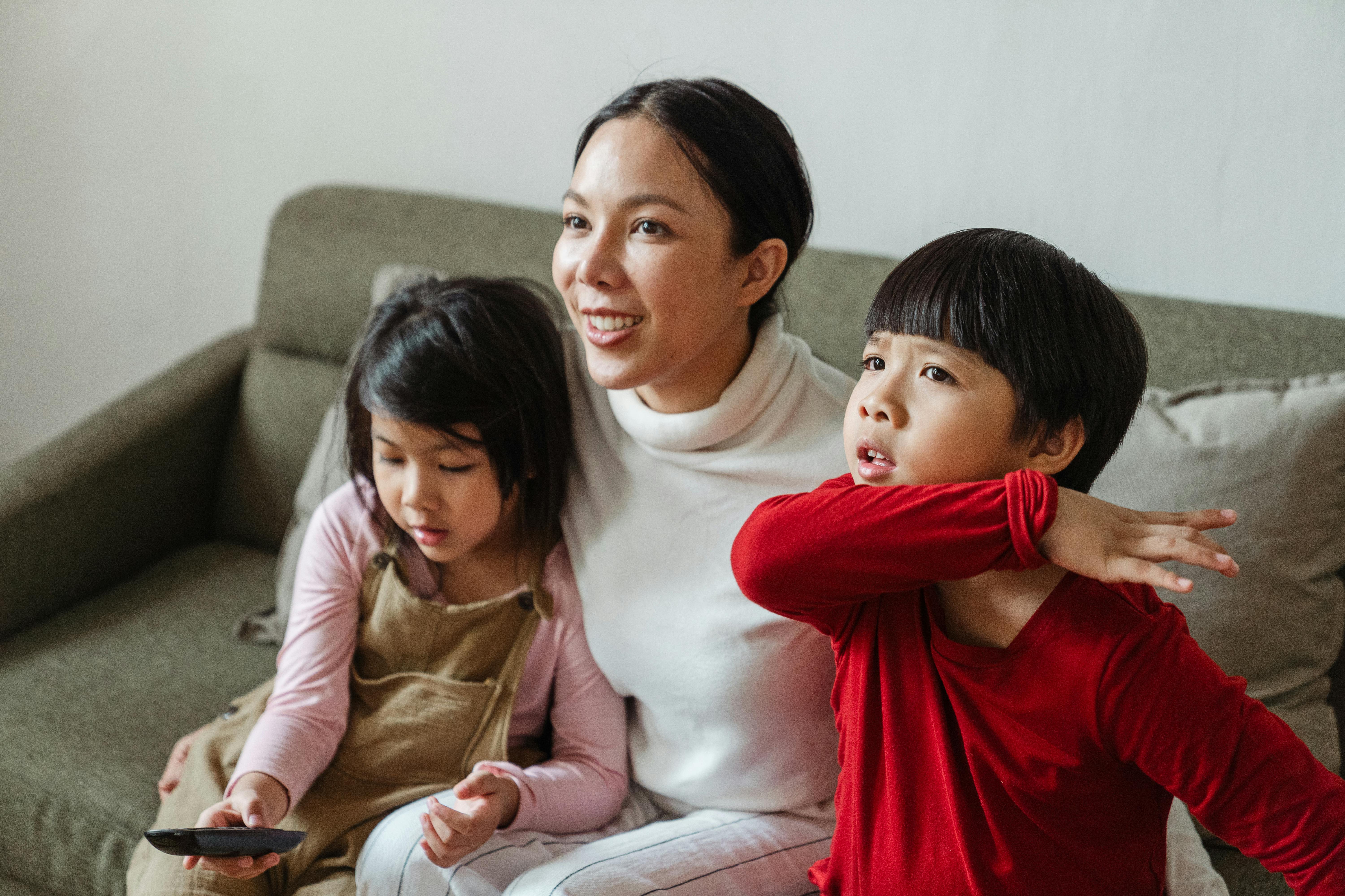 An adult and two children sitting on a couch together