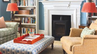 A patterned ottoman in a living room with a fireplace and clashing colourful patterns