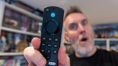 Amazon Fire TV Stick remote held by Rik Henderson in a home setting