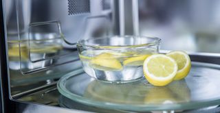 A microwave safe bowl filled with water and slices of lemon to show how to clean a microwave using lemons