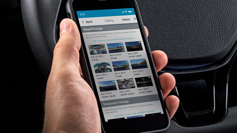 A hand holding a phone running the Garmin dash cam app