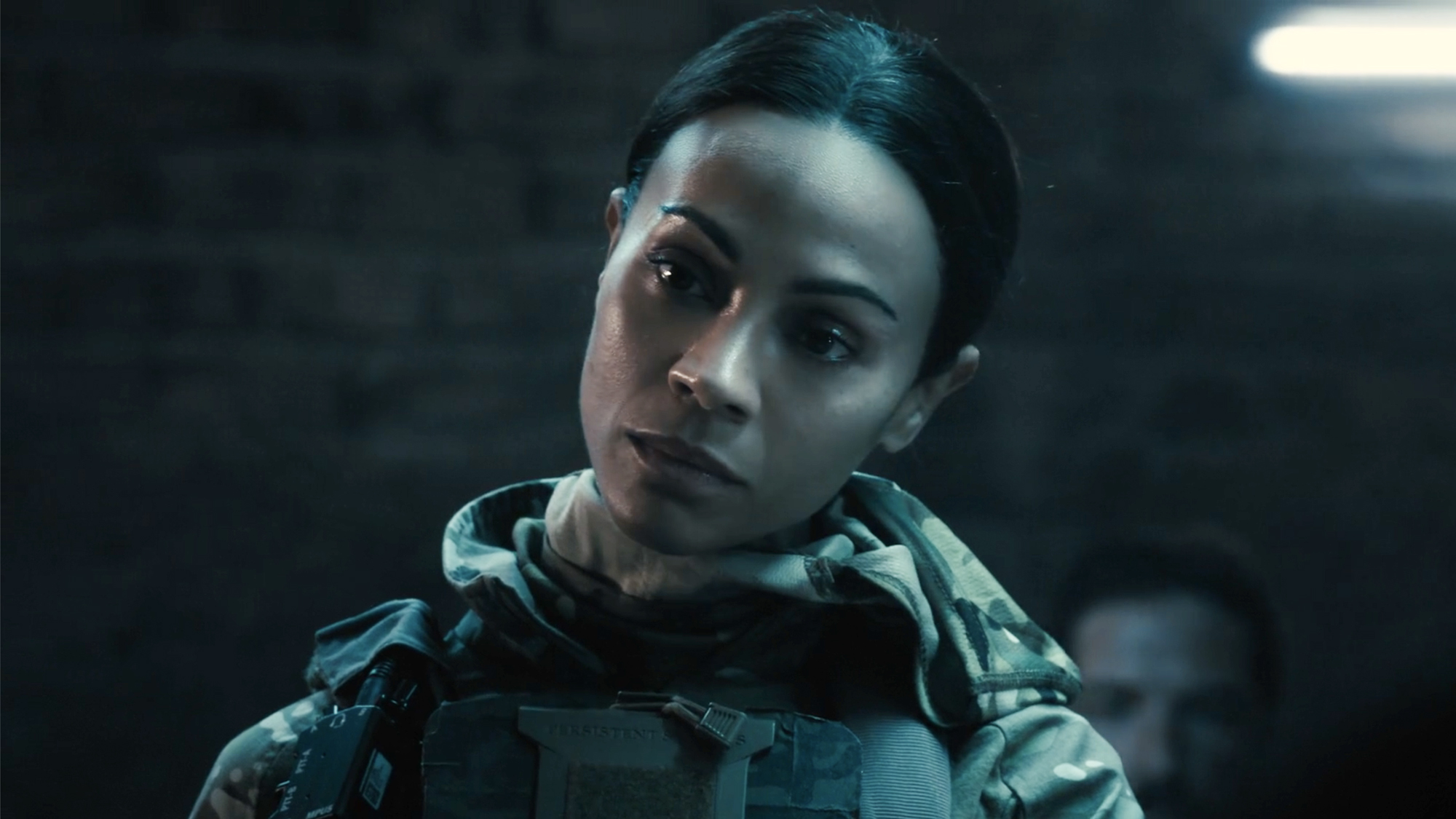 Zoe Saldana wearing military camo and swat gear with hair pulled back, Lioness season 3 episode 1 (2026).
