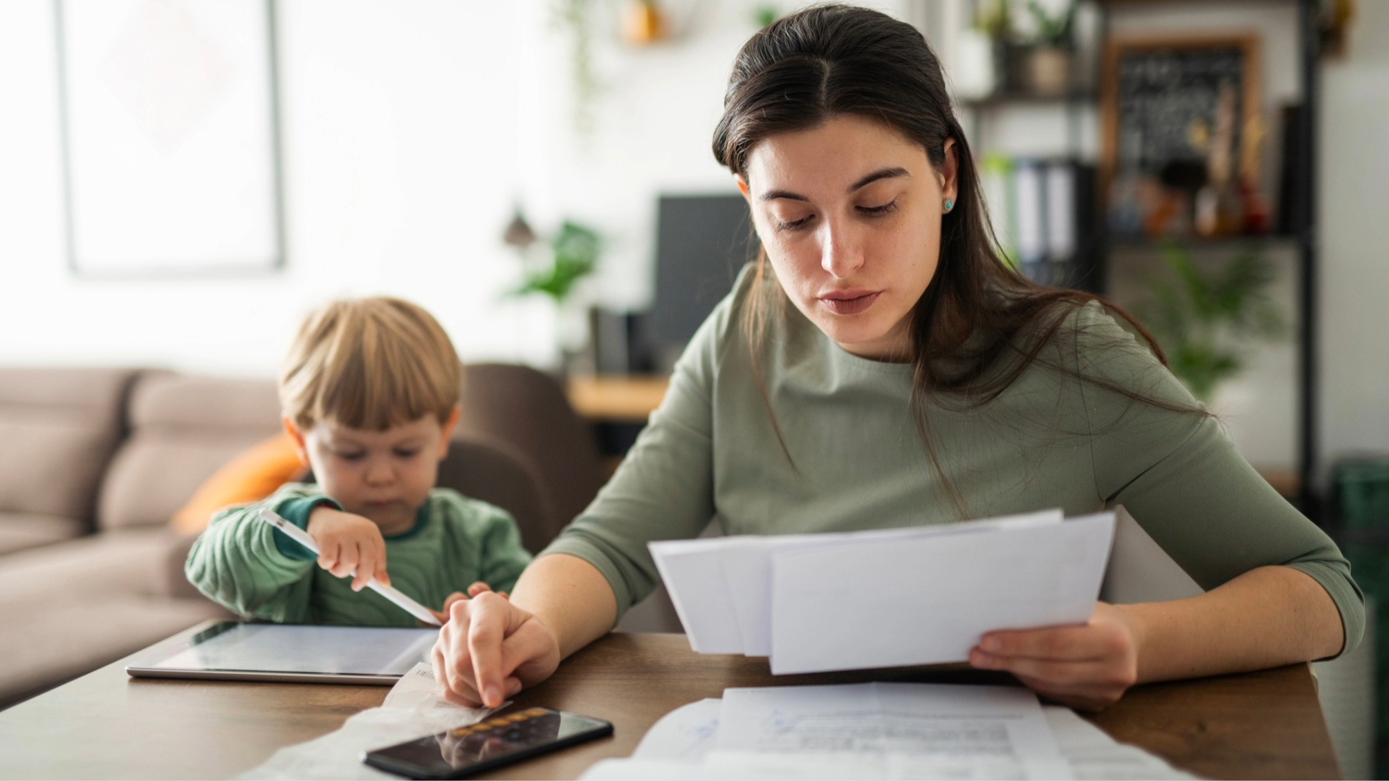 Single mother calculating budget with young son by her side. 
