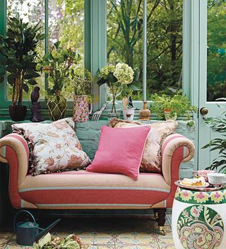 Green conservatory with pink snuggler sofa