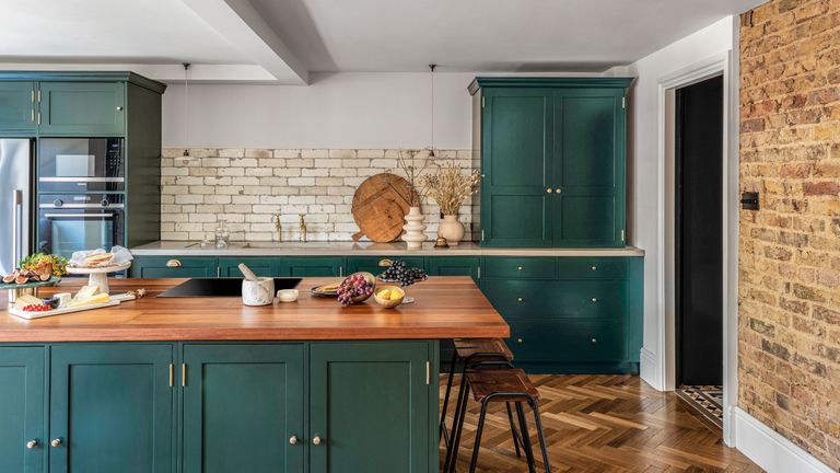 Dark green kitchen with exposed brick splashback