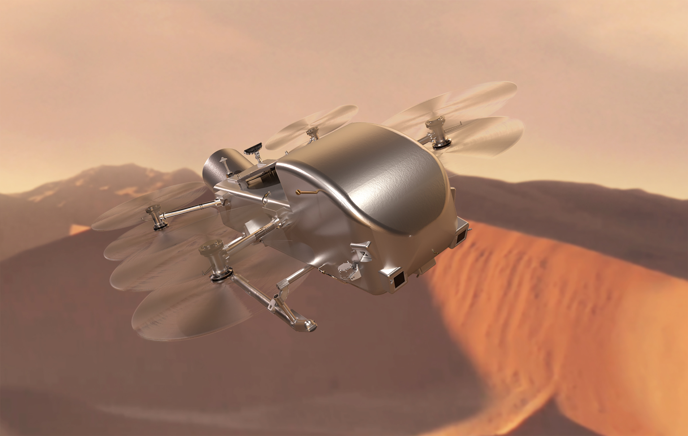Długi, chromowany dron z sześcioma śmigłami na poziomie ciała, przypominający ważkę.  Leci nad krajobrazem z różowymi/brązowymi wydmami.
