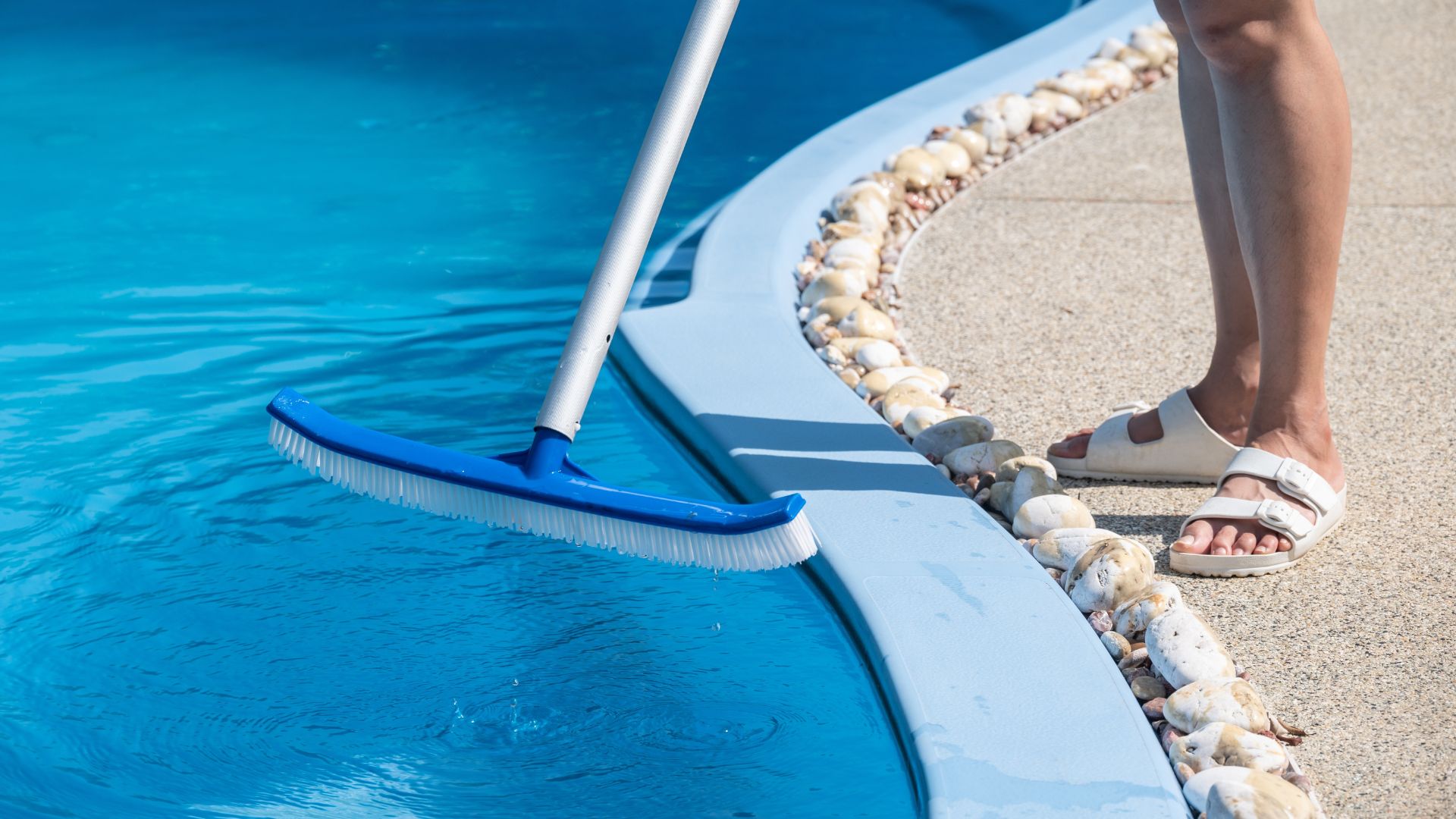 A person cleaning a pool with a brush
