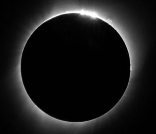 A black-and-white image of the total solar eclipse as seen from near Thermopolis, Wyoming. A solar flare is visible in the light of the corona surrounding the blacked-out sun.