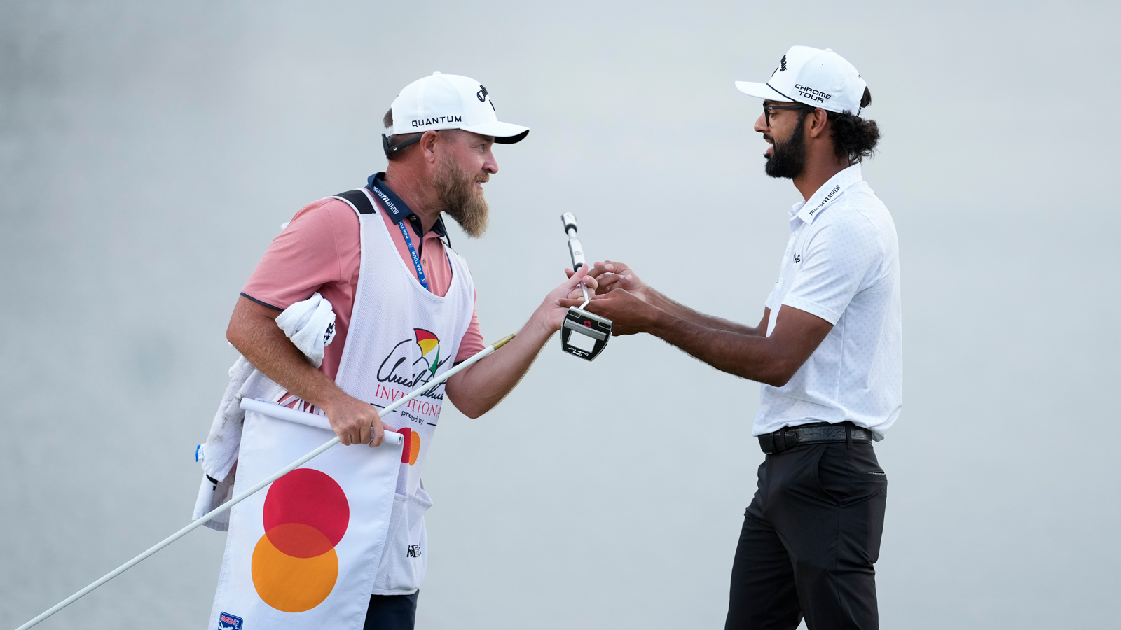 Akshay Bhatia hands his putter to his caddie