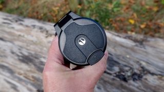 Pulsar Telos XQ35 monocular held in a hand outside in front of a log