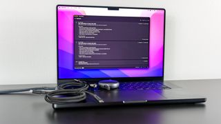 A MacBook Pro running the WhatCable app with several cables on top of its keyboard