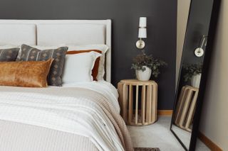 A bed with a mirror and a nightstand with green foliage