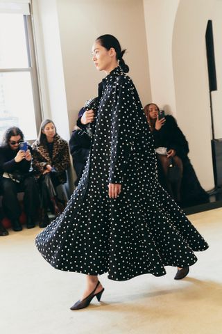 A model walking in the Altuzarra show wearing a polka dot dress with slingback pumps.