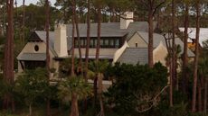 a vast home with stone architecture and chimneys surrounded by trees on Kiawah Island