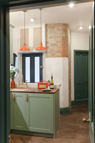 green small kitchen and orange pendant lights by Brooke Copp-Barton light