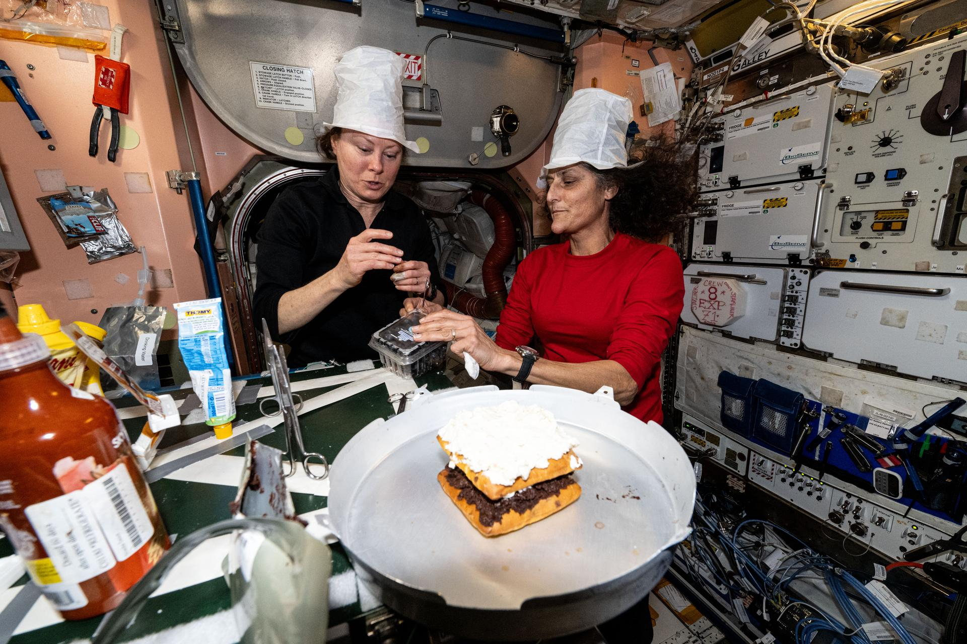 NASA astronauts Tracey Caldwell Dyson and Sunita Williams create an ice cream concoction on the International Space Station.