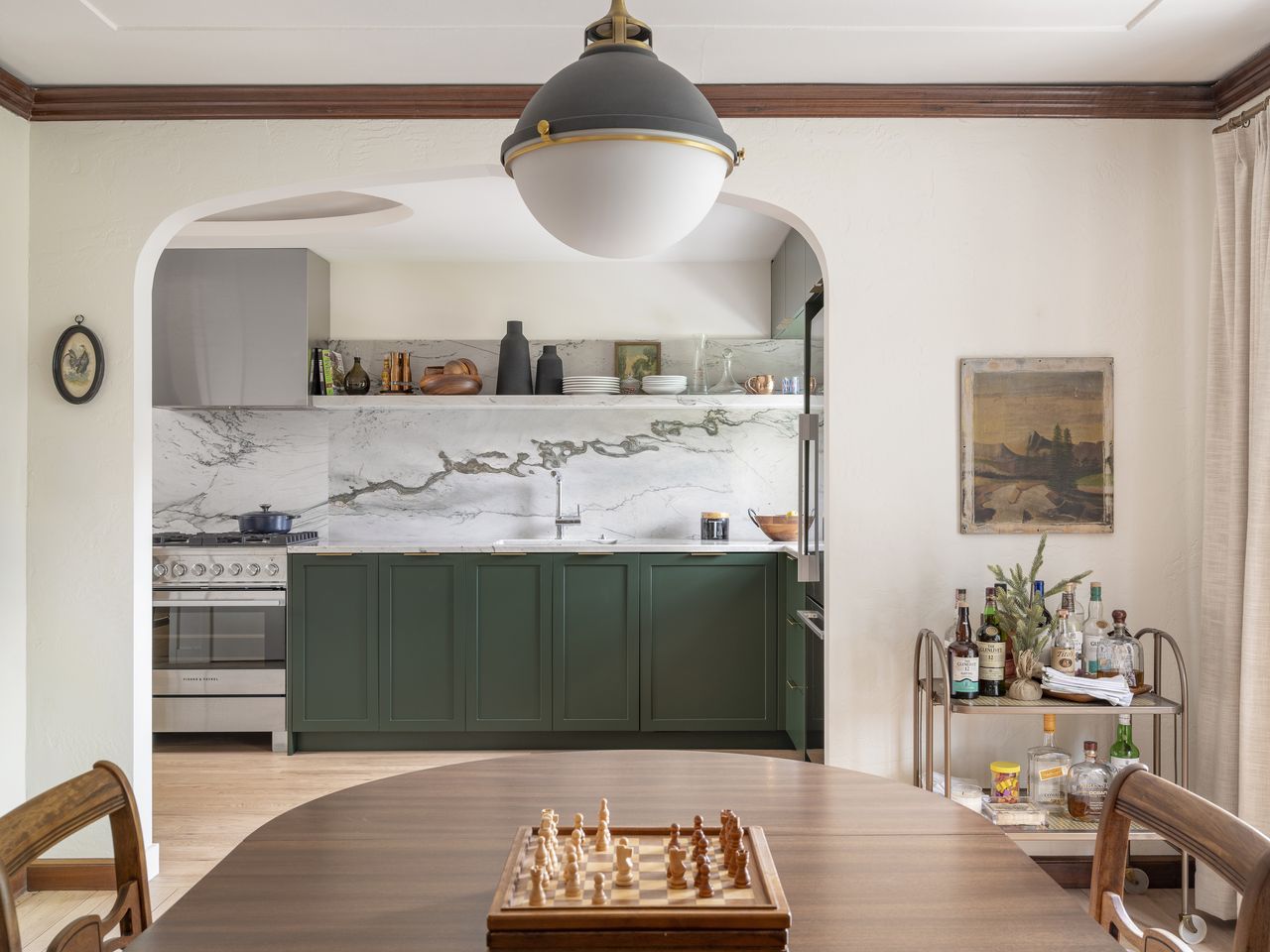 A kitchen in green, with an arched door that opens to the dining room