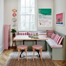 banquette seating small corner of open plan kitchen with pink white and green artwork which defines the scheme of the green banquette pink and white striped cushions