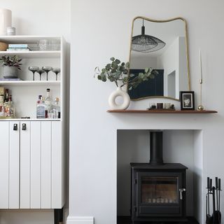 White dining room with woodburner, mirror hanging above mantelpiece