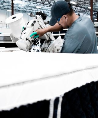 From behind: a factory worker tinkering with a machine in the 3Z mattress factory.