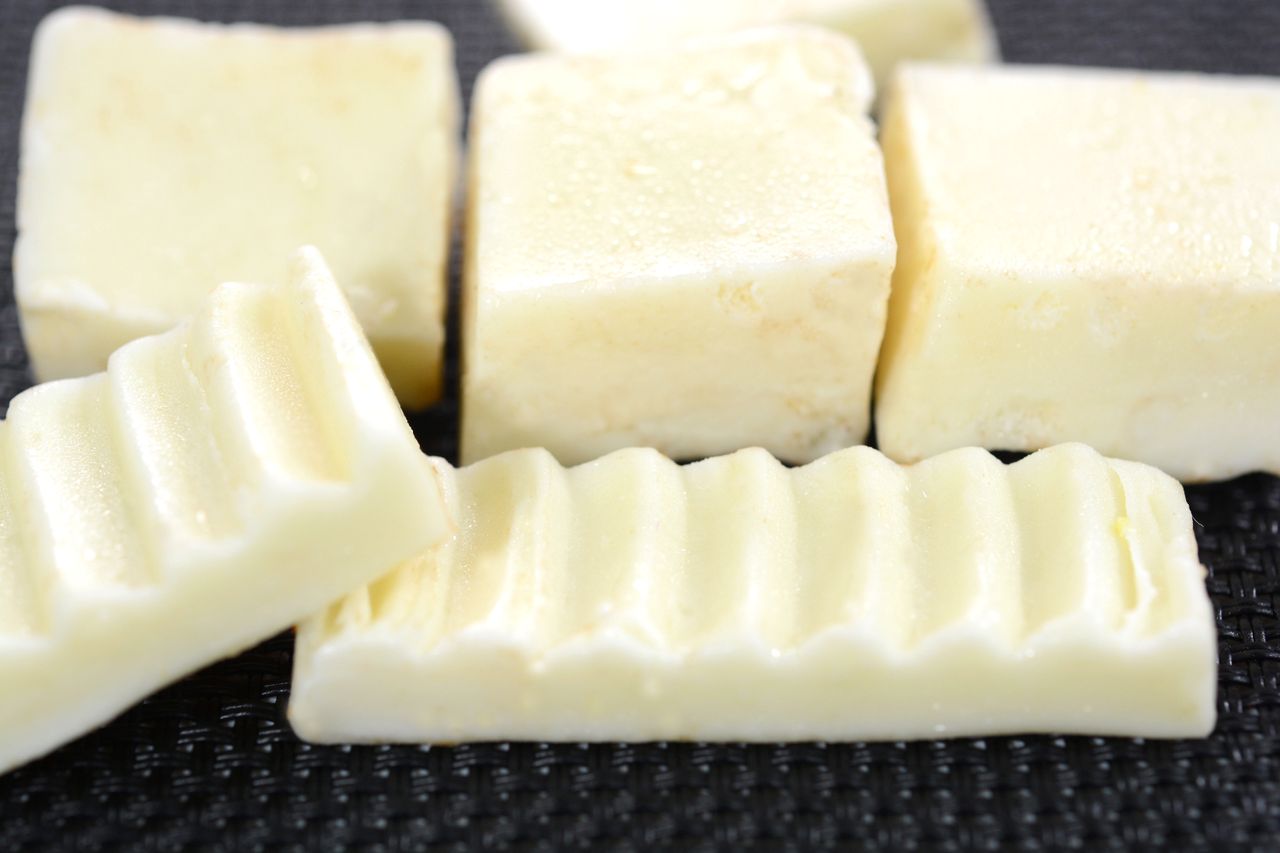 Pieces of white chocolate microwave fudge and white chocolate in front