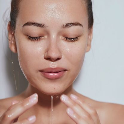 Woman washing face with water