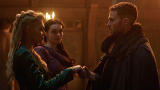 Jordan Alexandra in a green dress as Guinevere stands opposite Iain De Caestecker as Arthur in a fur cloak as Arthur in The Winter King.