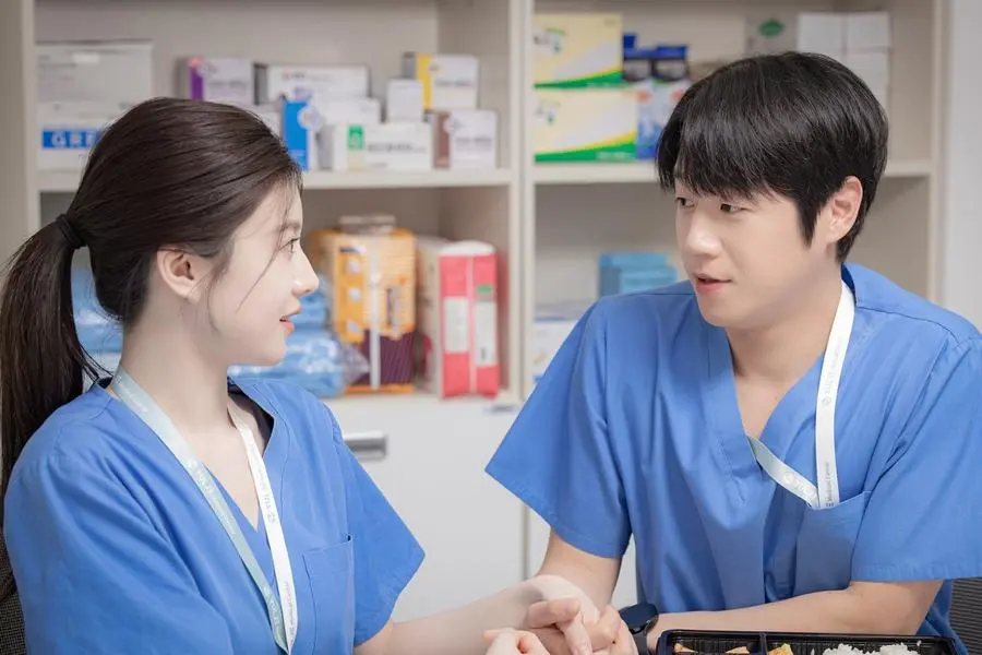 Two doctors hold hands while sitting in an office, in 'Resident Playbook.'