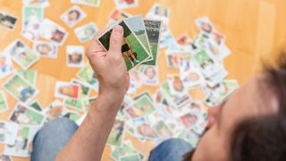 Man holds trading cards while sitting amongst several others