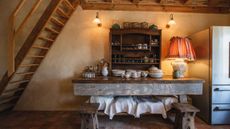 Farmhouse kitchen with beams, wall sconces, antique dresser and table with vintage china and dishes