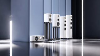 Wharfedale EVO 5 speakers in white against a light blue background. The dark floor is highly reflective and the speakers are brightly lit