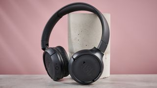 JBL Tune 510BT leaning against pillar on pink background