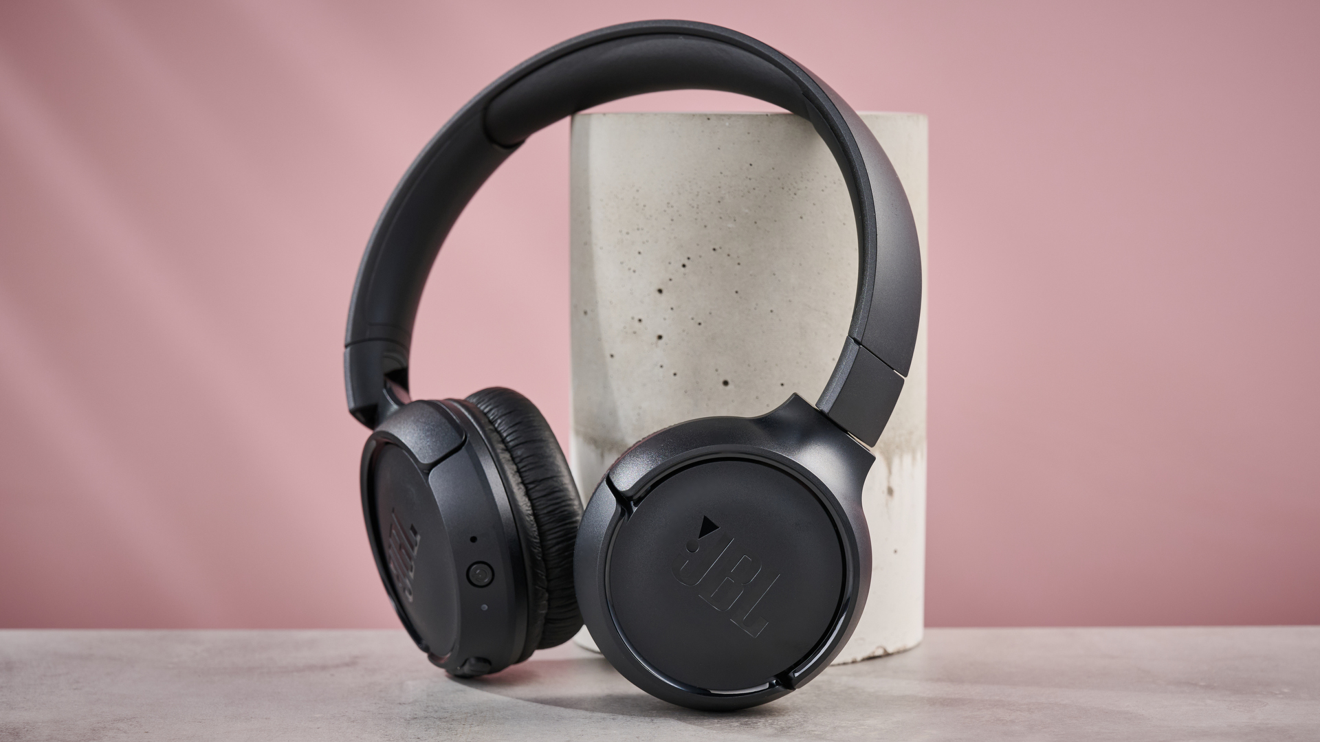 JBL Tune 510BT leaning against pillar on pink background