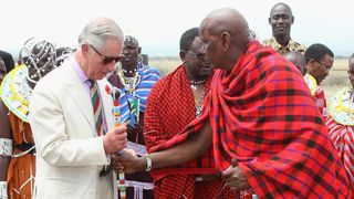 Prince Charles, Prince of Wales is presented with a traditional Maasai stick during a visit to Majengo Maasai Boma