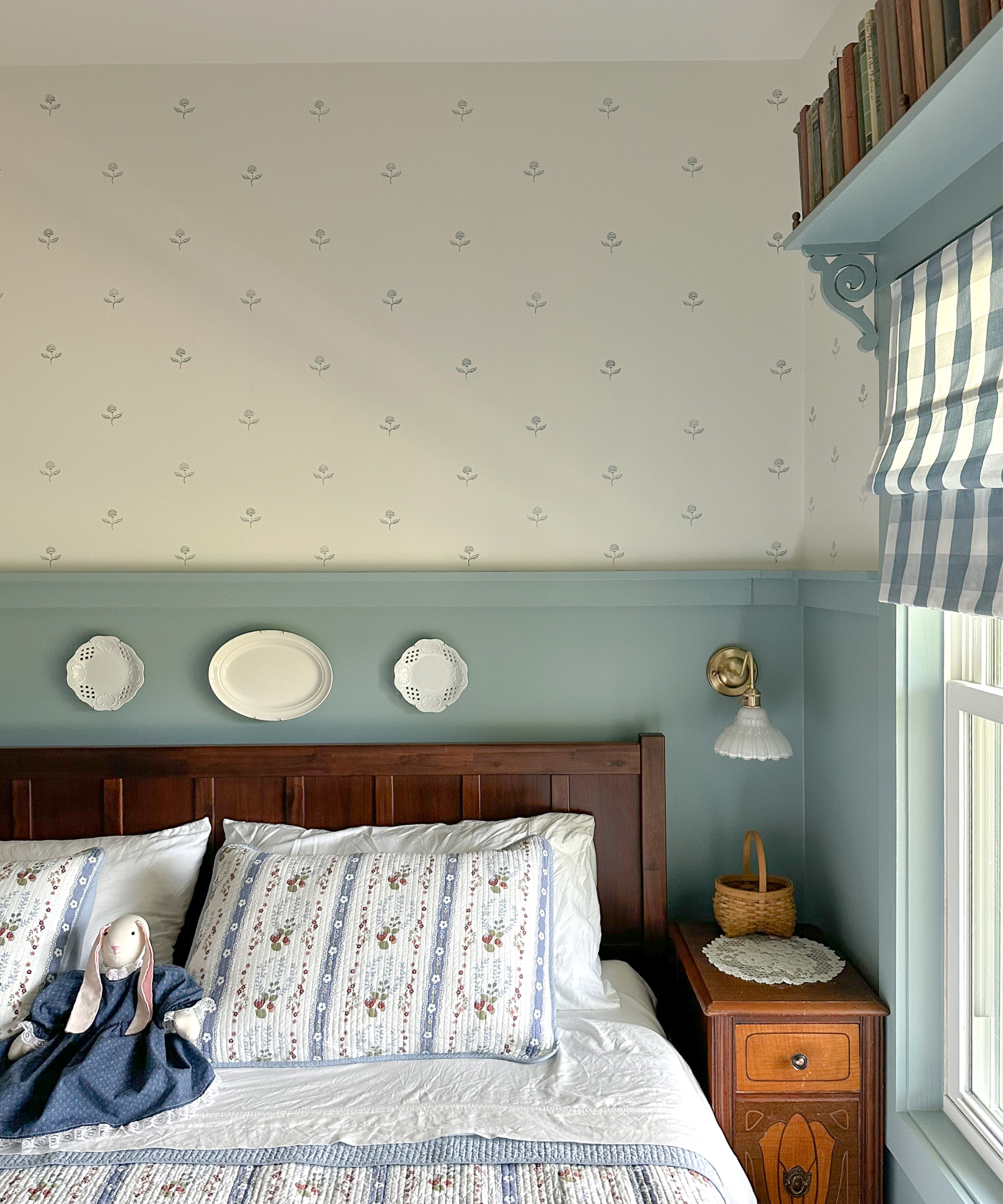 a bedroom with a wooden bed, blue and white walls, and vintage bedding