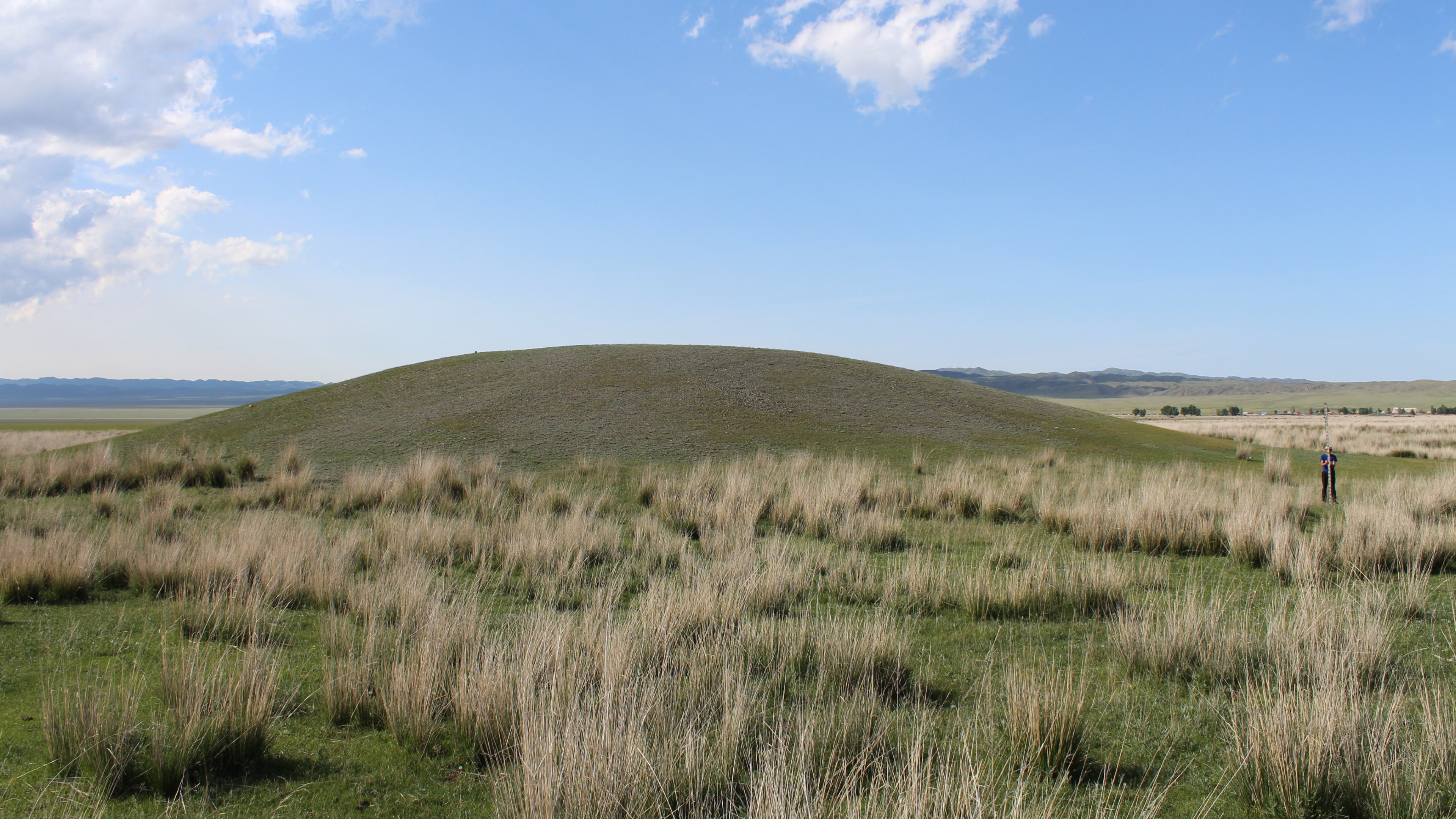 a grass-covered mound against a blue sky