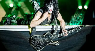 Paul Stanley of KISS dangles his cracked-mirror finish Ibanez Iceman off the stage as he lies on the stage at Download Festival.