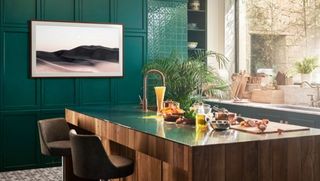 SAMSUNG The Frame QE55LS03AAUXXU 55 Smart 4K Ultra HD HDR QLED TV in a stylish modern kitchen with green panelled wall and wooden island