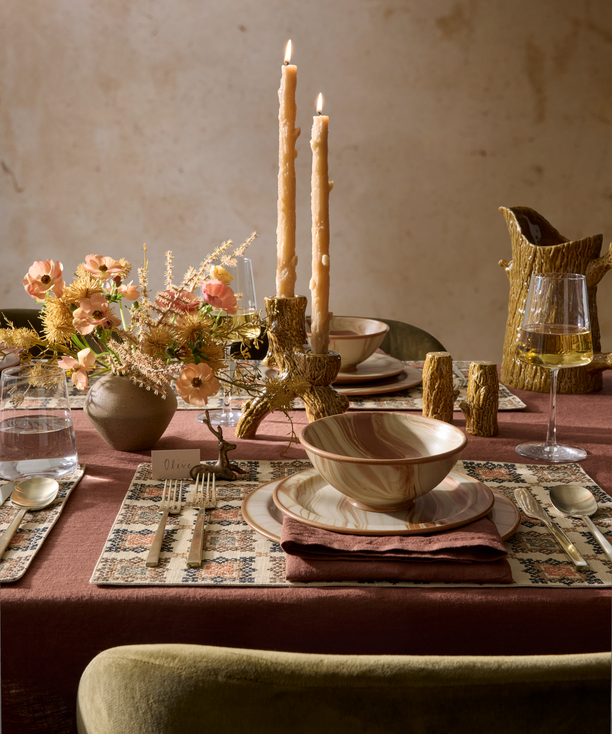 a woodland inspired tablescape with earth-toned decor, marbled dinnerware, and a small bouquet of flowers