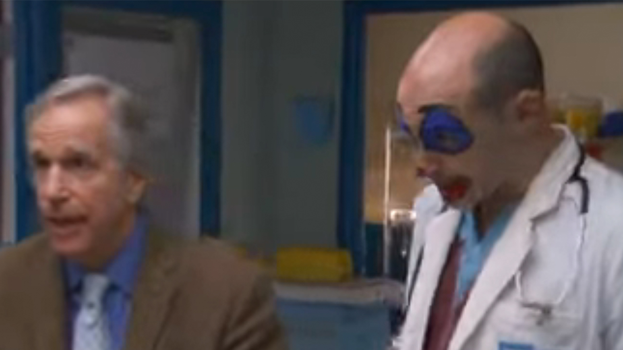 Henry Winkler in a suit standing next to Rob Corddry in clown make up on Childrens Hospital