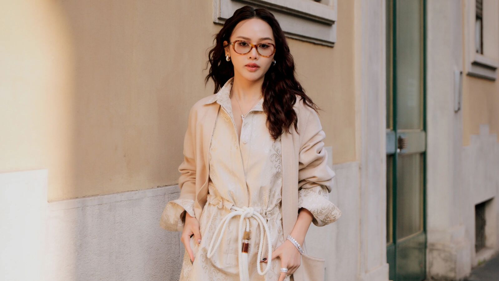Woman wears trench coat with shirt dress in Milan. 