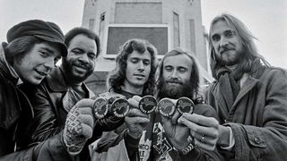Genesis holding pins which read "Rainbow, Rock Again" outside the Rainbow Theatre in London, UK, January 1977