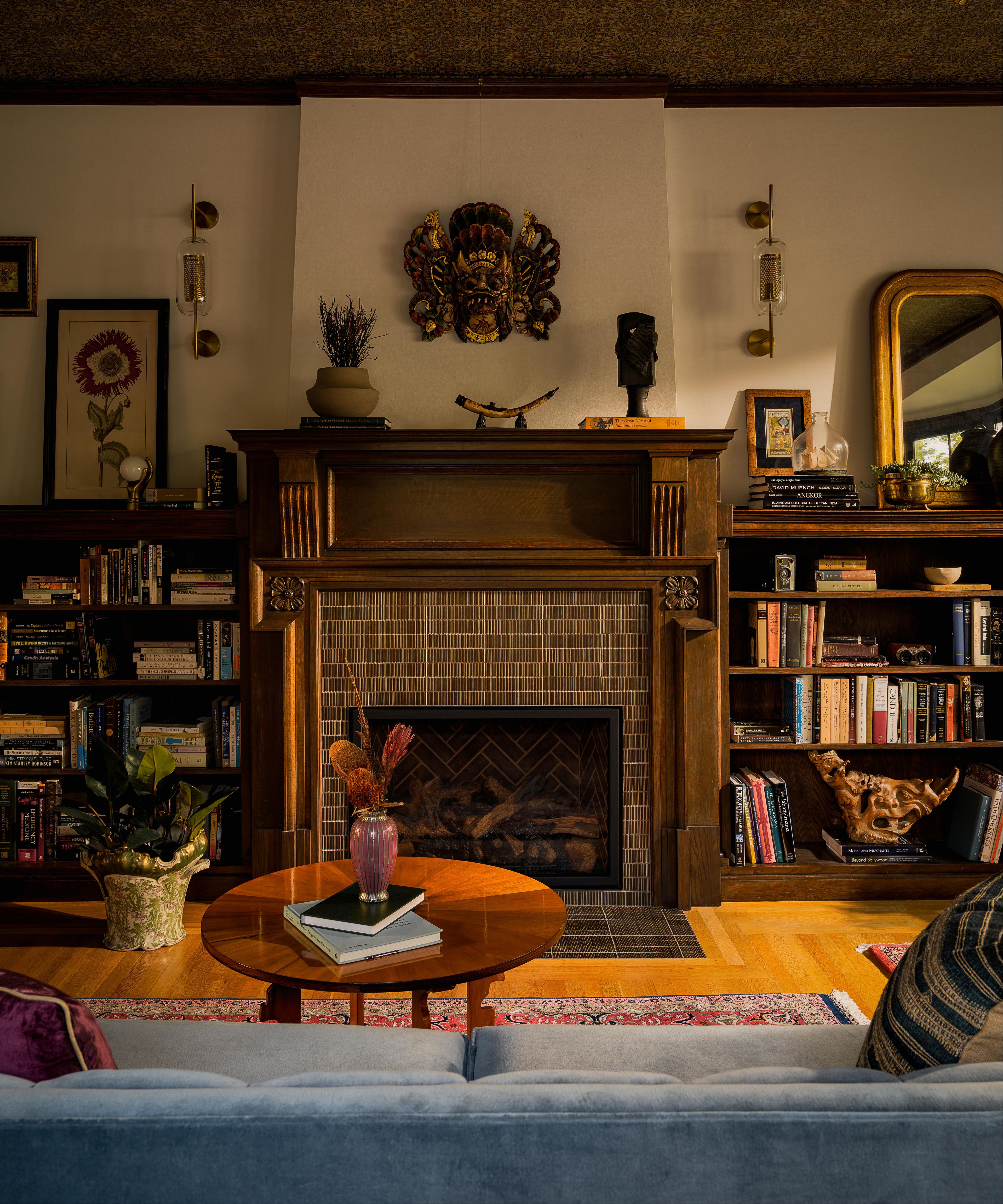 a moody home library with a wallpapered ceiling and original tudor fireplace