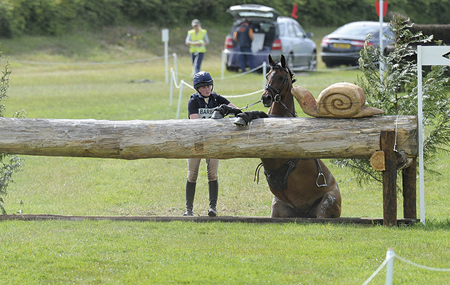 Katey Cuthbertson riding IMBROGLIO having a rest at the over hanging log in the CIC ** during the Barbury International Horse Trials at Sharpridge Farm, Rockley, near Marlborough in Wiltshire, UK on 11 July 2015