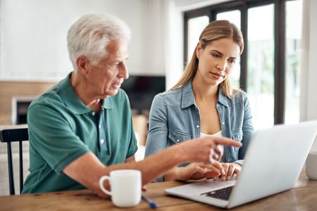 A senior man is going over his finances with the help of his adult daughter.