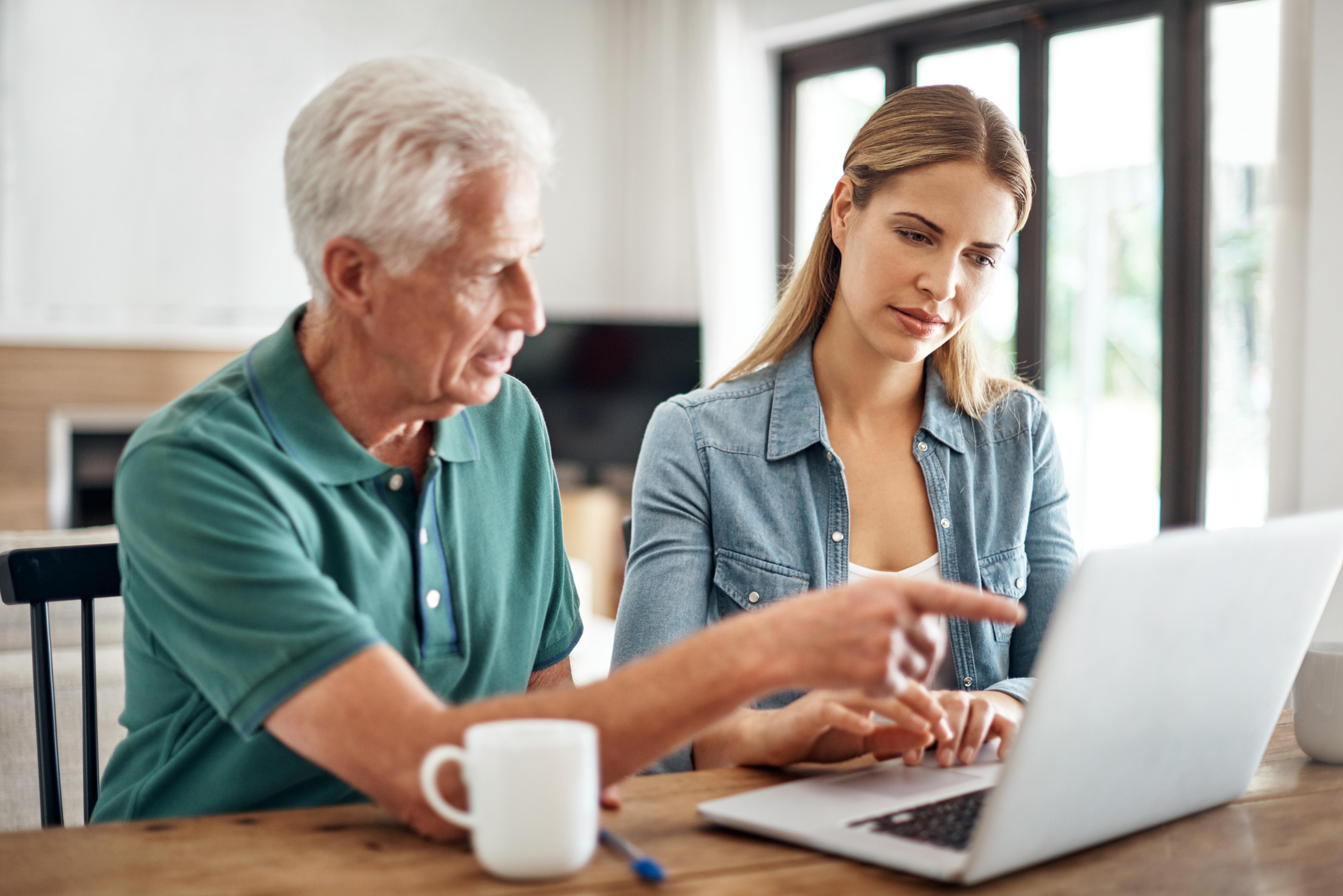 A senior man is going over his finances with the help of his adult daughter.